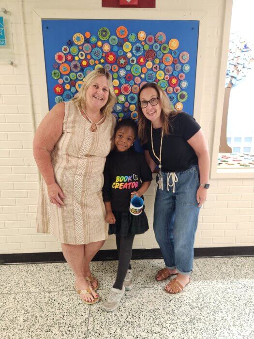 Angela smiling in her book creator tshirt with her favorite educators. 